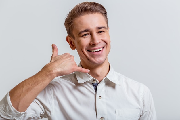 Man is smiling and imitating phone with his hand.