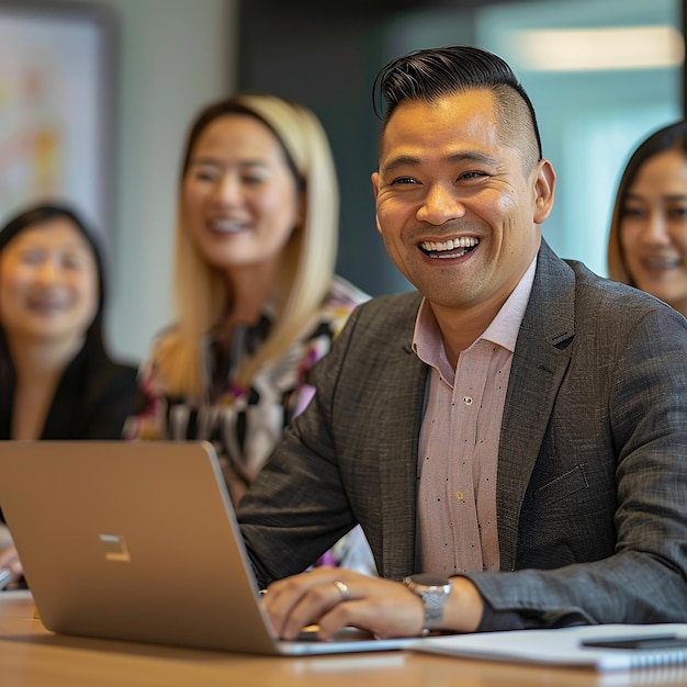 a man is smiling while sitting in front of a laptop