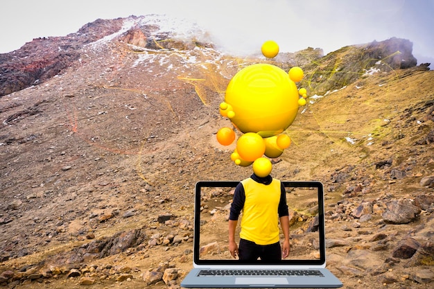 A man is standing in front of a computer with a yellow ball on it.