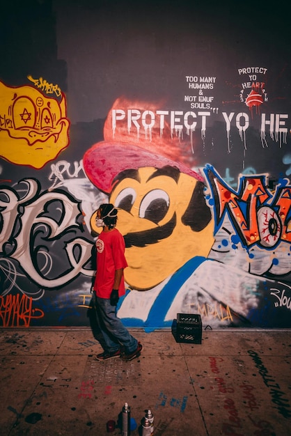 Photo a man is standing in front of a graffiti wall that says keep me happy