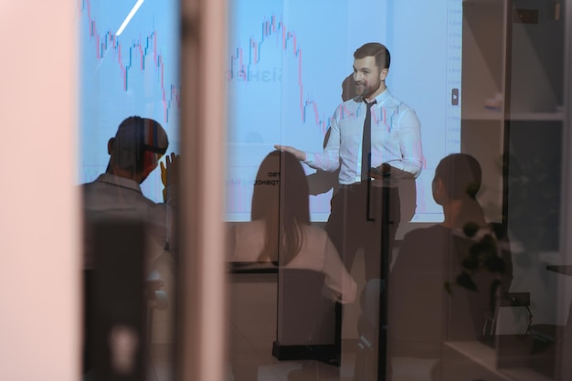 Man is standing near projector and showing graphs and business graphs