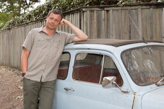 Man is standing near a vintage car on the beach