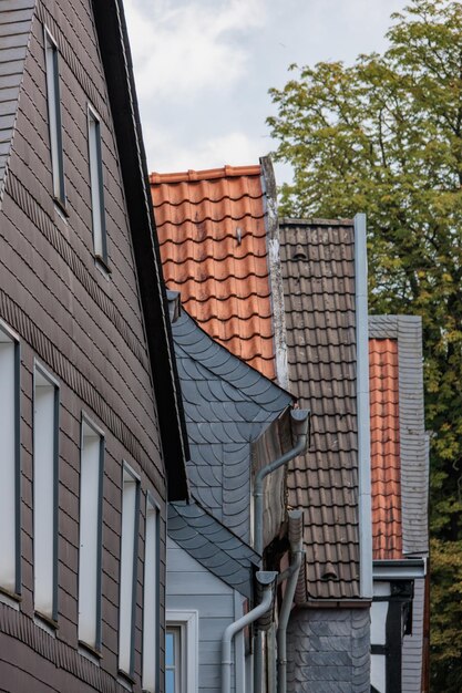 Photo a man is standing on a sidewalk next to a house with a red roof