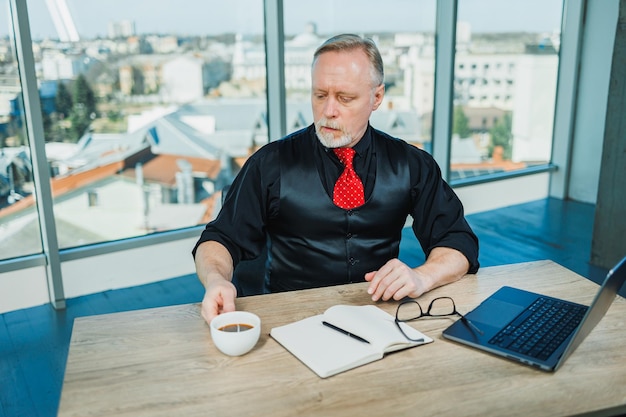 Photo the man is a stylish freelancer a grayhaired businessman on a workplace in the office adult bearded boss in the office