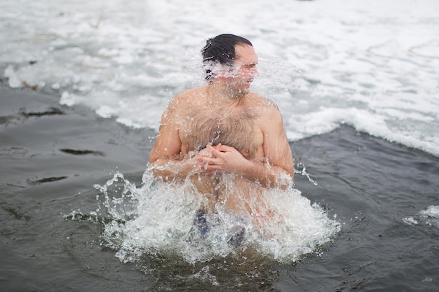 The man is swimming in an ice hole.