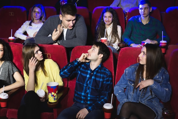 A man is talking loudly on the phone in a movie theater and prevents you from watching a movie. The man makes a remark and asks to turn off the phone.