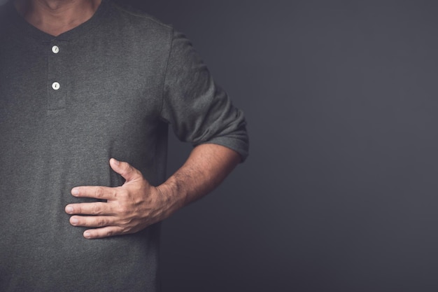 Man is using his hand to cover over left side of stomach because of hurt pain or feeling ill Injuries or Illnesses that can happen to people while working Kidney disease or Stomachache concept