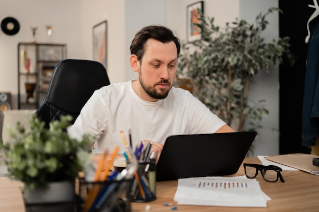 A man is working on his new project on a laptop he is completely focused on work