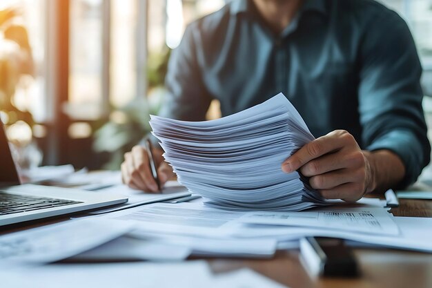 Photo a man is writing in a stack of papers with a pen in his hand