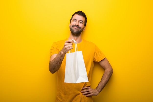 Man on isolated vibrant yellow color holding a lot of shopping bags