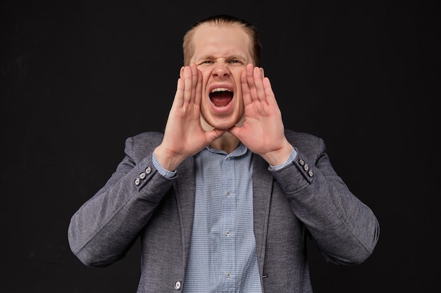 A man in a jacket screams on a black background.