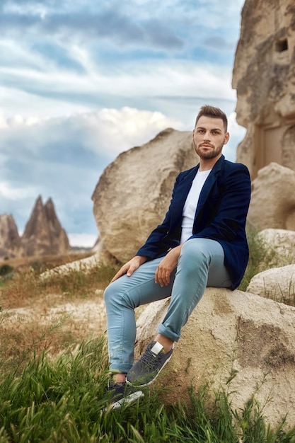 Man in a jacket with a beard sitting in the nature.