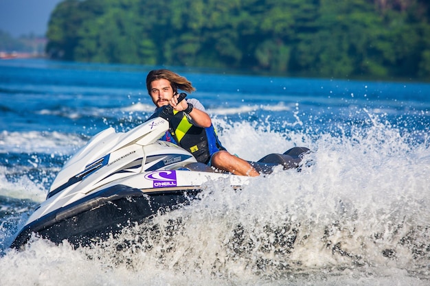 Photo a man on a jet ski in the water with a purple and green life jacket