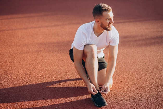 Man jogger tying shoelaces at stadim