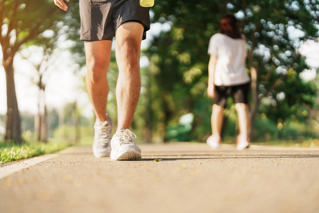 Man jogging and walking on the road at morning with Energy Drink water adult male in sport shoes running in the park outside Exercise wellness healthy lifestyle and wellbeing concepts