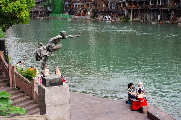 Man jump statue to tuojiang river in Historical building heritage architecture of Xiangxi Phoenix Ancient City or Antique Old Town fenghuang for chinese travelers visit on May 9 2024 in Hunan China