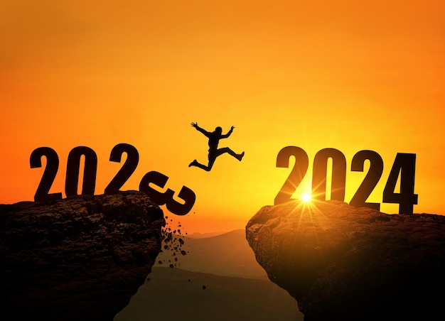 Man jumping on cliff 2024 over the precipice with stones at amazing sunset New Year's concept 2023 falls into the abyss Welcome 2024 People enters the year 2024 creative idea