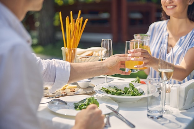 man keeping glass with orange lemonade in hand at the dining table