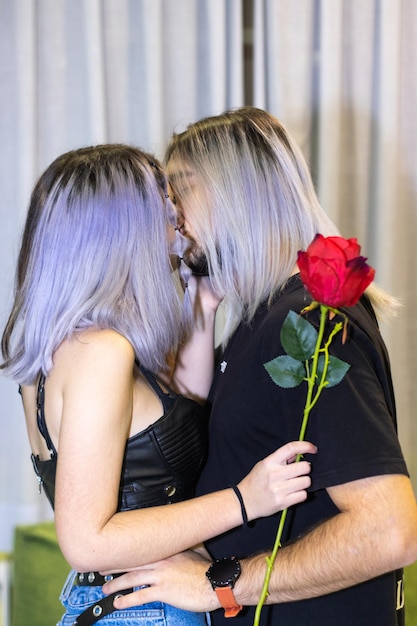 Man kissing his girlfriend at home while the girl is holding a rose Guy kissing his girlfriend while she is holding a rose