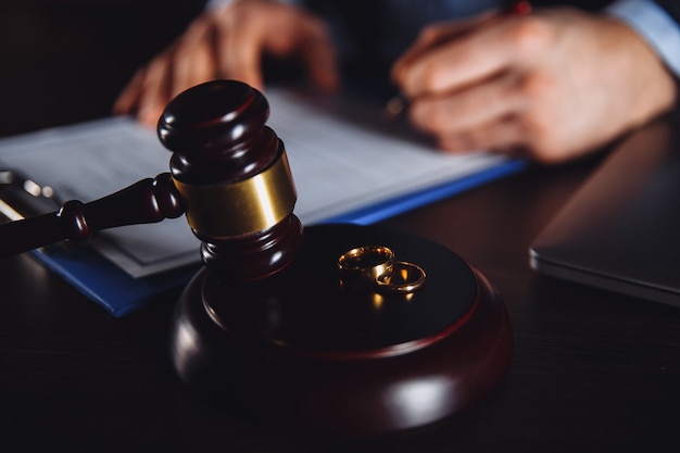 Man lawyer working with paper contract. Wooden gavel and libra on the desk.