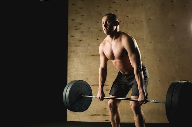 Man lifting weights. muscular man workout in gym doing exercises with barbell