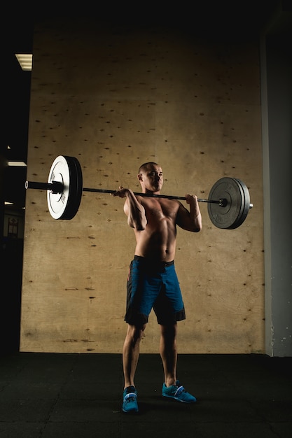 Man lifting weights. muscular man workout in gym doing exercises with barbell