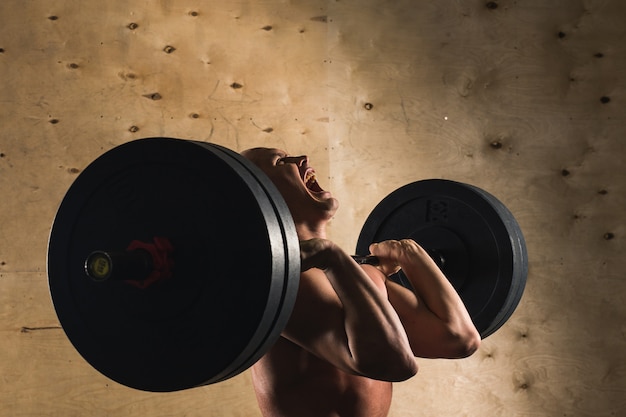 Man lifting weights. muscular man workout in gym doing exercises with barbell