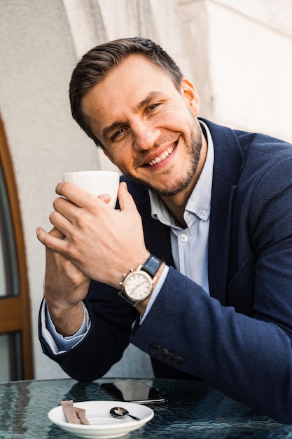 Man like coffee Handsome man with cup of coffee in cafe Morning lifestyle of male Man is sitting on the summer terrace in cafe drinking coffee and smiling