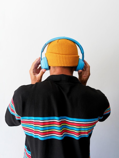 Man listening blue headphones white background Back view