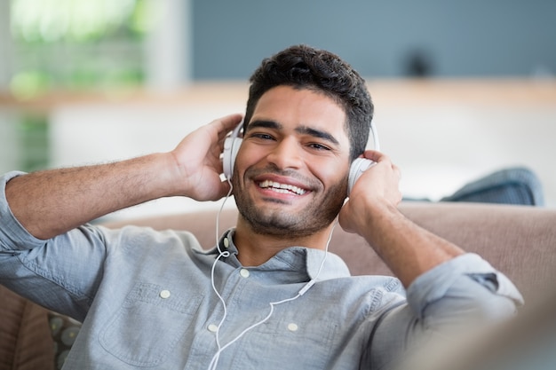 Man listening to music on headphones in living room at home