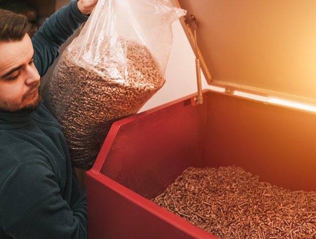 Man loading up pellet heating stove Worker in a boiler room filling wooden pellet boiler Biomass heating system