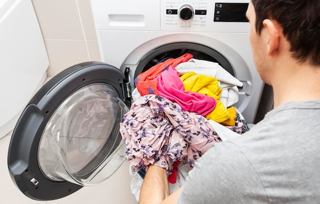 Man loading the washer dryer with clothes with different color and type