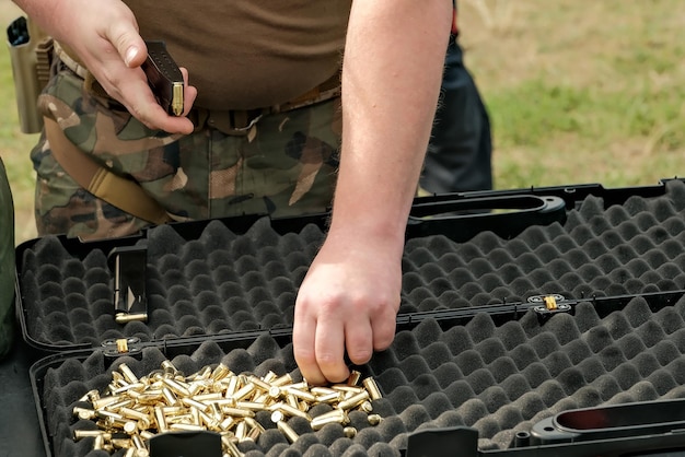 A man loads cartridges into a clip live ammunition and pistol