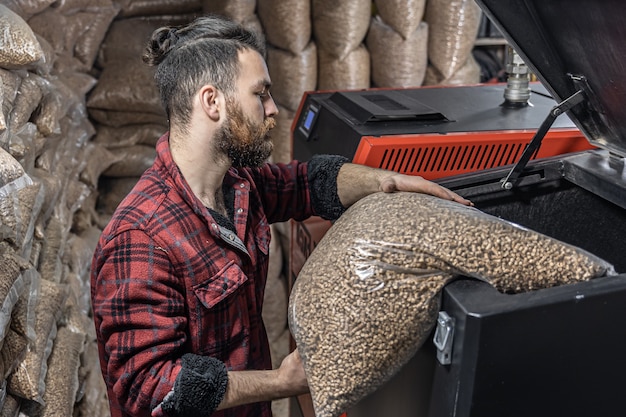 The man loads the pellets in the solid fuel boiler working with biofuels