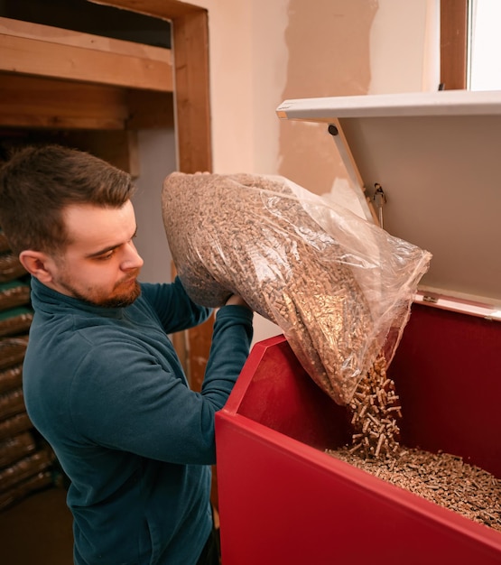 Man loads wood pellets in the solid fuel boiler Concept of heating stove working with biofuels and economical heating