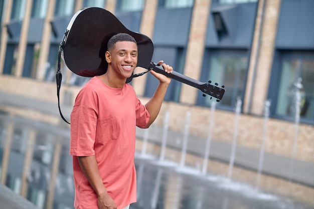 Man looking at camera holding guitar on his shoulder