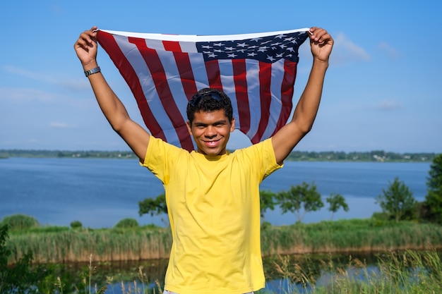 Man looking at camera and proudly holding american flag in his arms