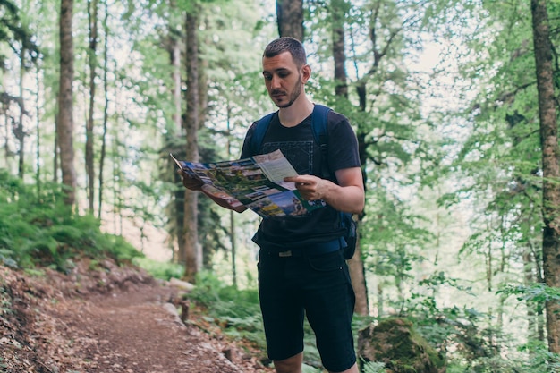 Man looking at the map while hiking in forest