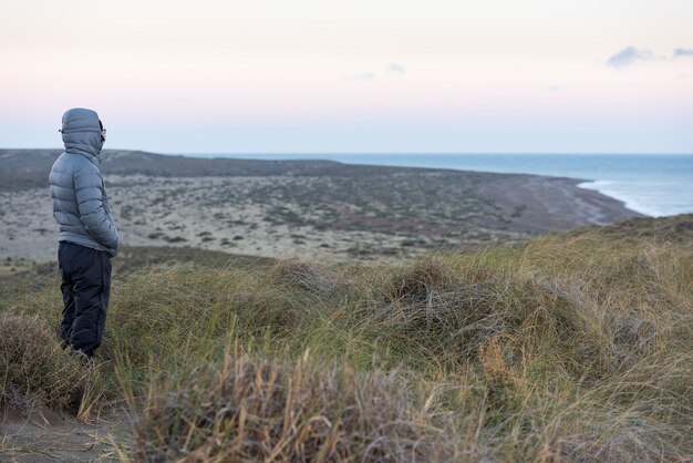 Man looking at pink sunrise in patagonia beach