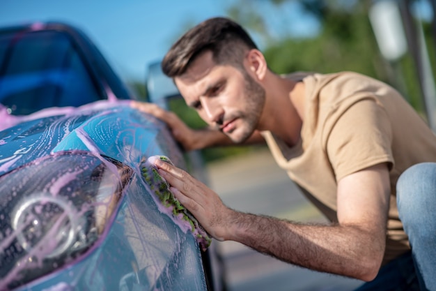 Man looking at wiped surface of car