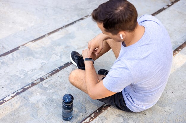 Man looking at workout results on fitness bracelet while resting after workout