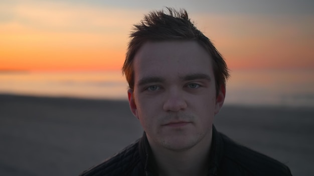 A man looks at the camera against the backdrop of a sunset