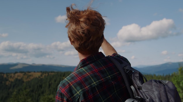 A man looks at a mountain view from the top of a mountain.