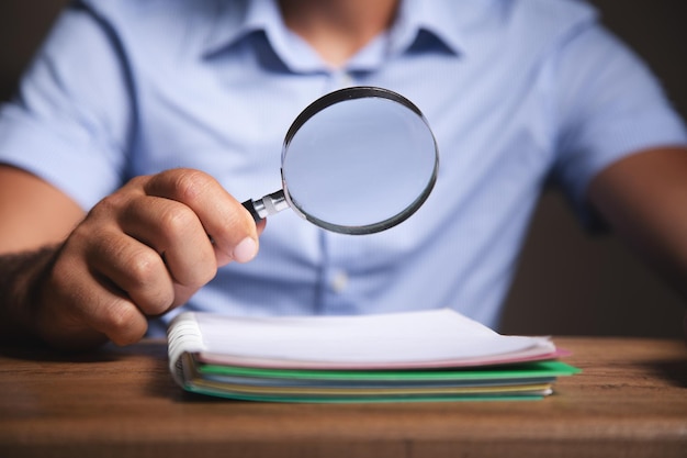 Man looks at papers with a magnifying glass