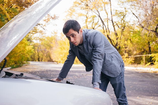 A man looks under the quota of a broken car