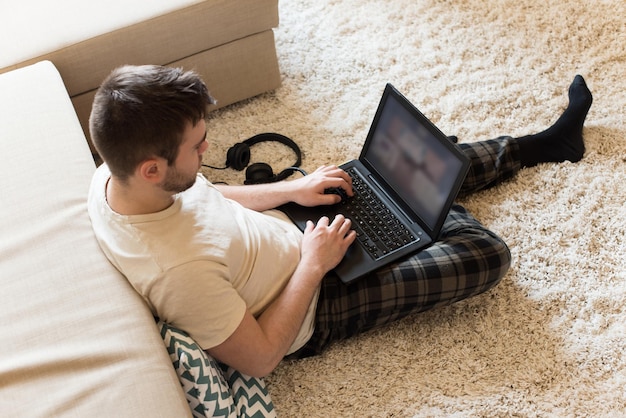 Man lying on the floor typing on laptop - Focus on laptop