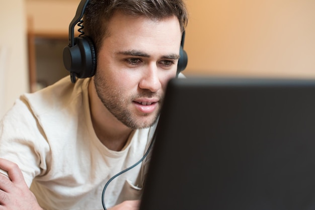 Man lying on the floor using headphones on laptop