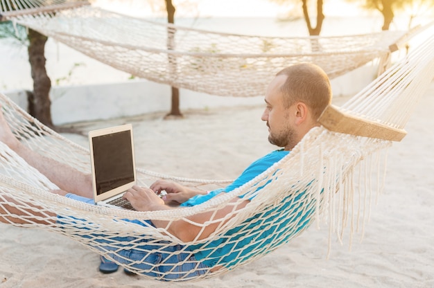 A man lying in a hammock overlooking the ocean