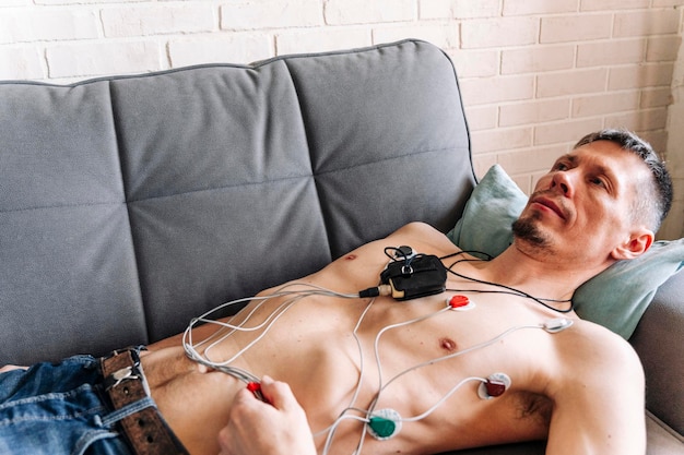 Man lying on a sofa with a Holter heart monitor connected