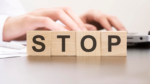 Man made word STOP with wood blocks on the background of the office table selective focus business concept